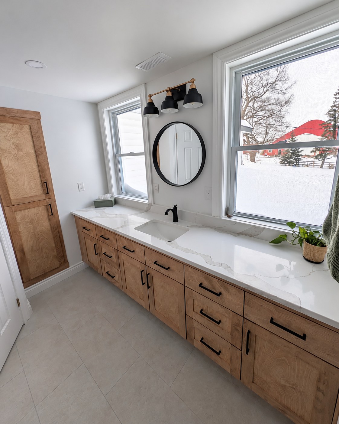 Wood bathroom vanity with drawers beneath two windows.