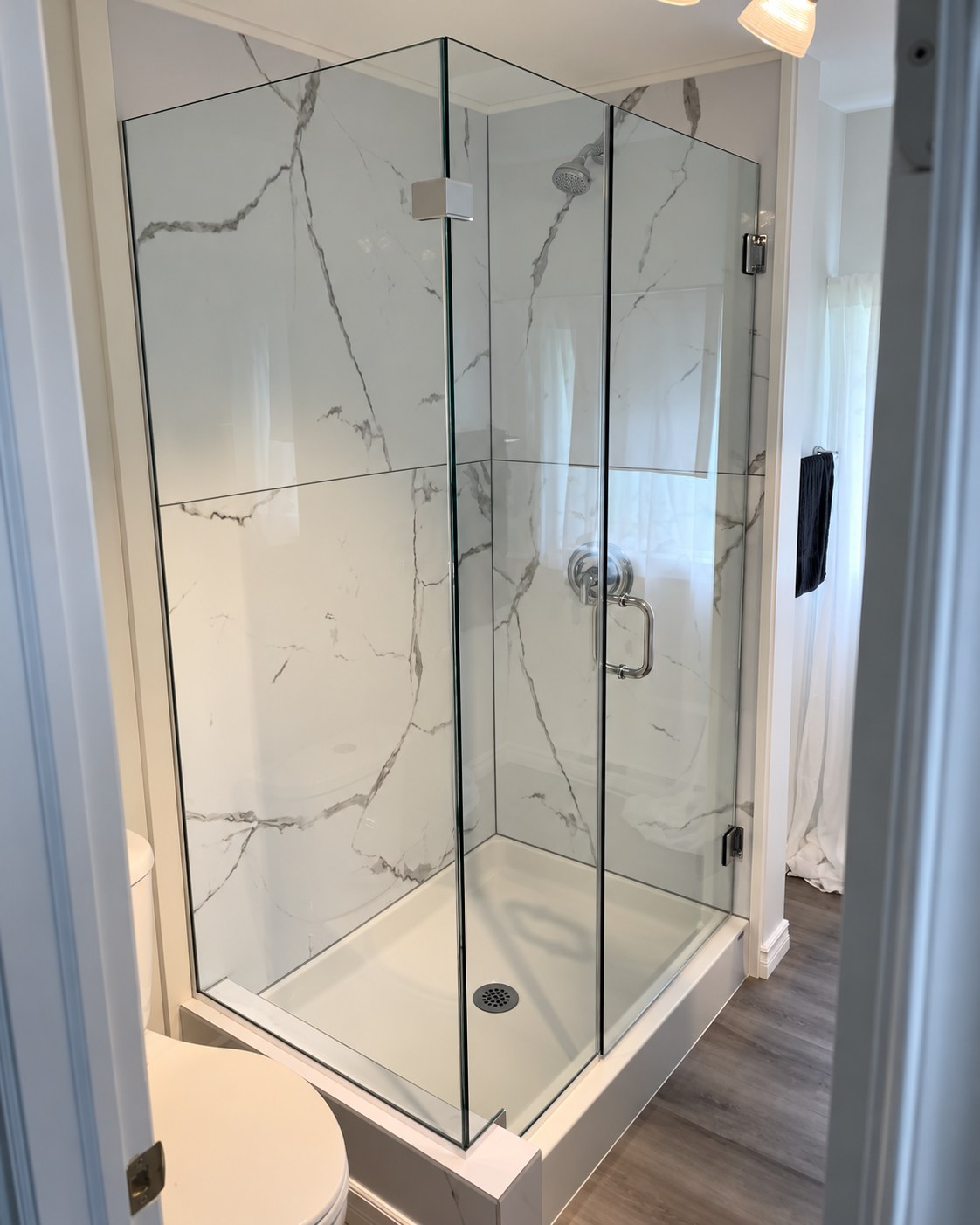 Corner shower enclosure with marble-look wall panels.