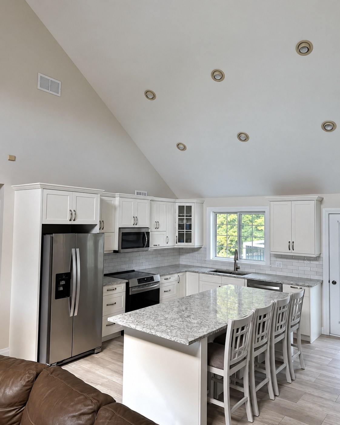 White kitchen cabinetry, stone-look counters and island seating.