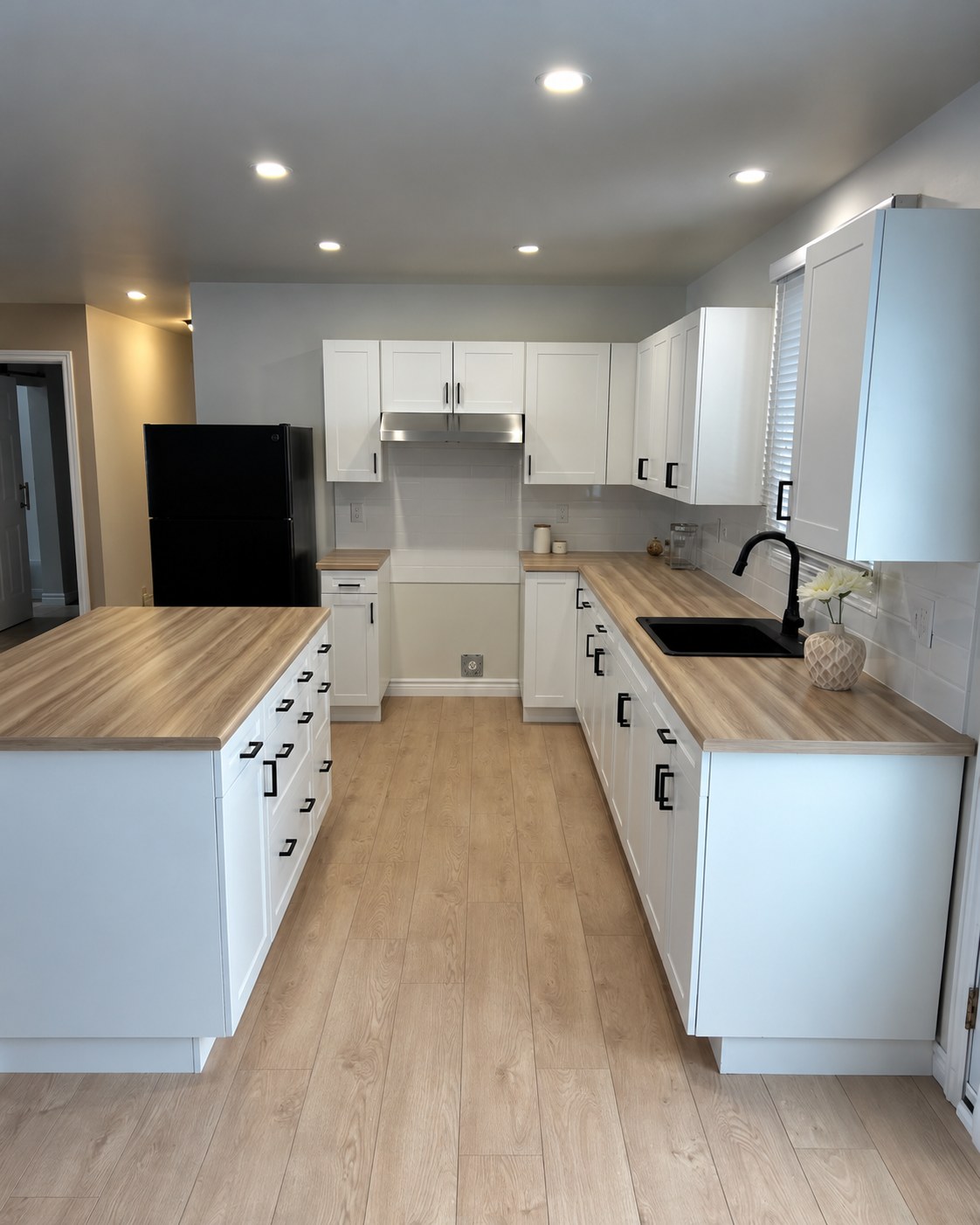 White kitchen cabinetry with wood counters and a black sink.