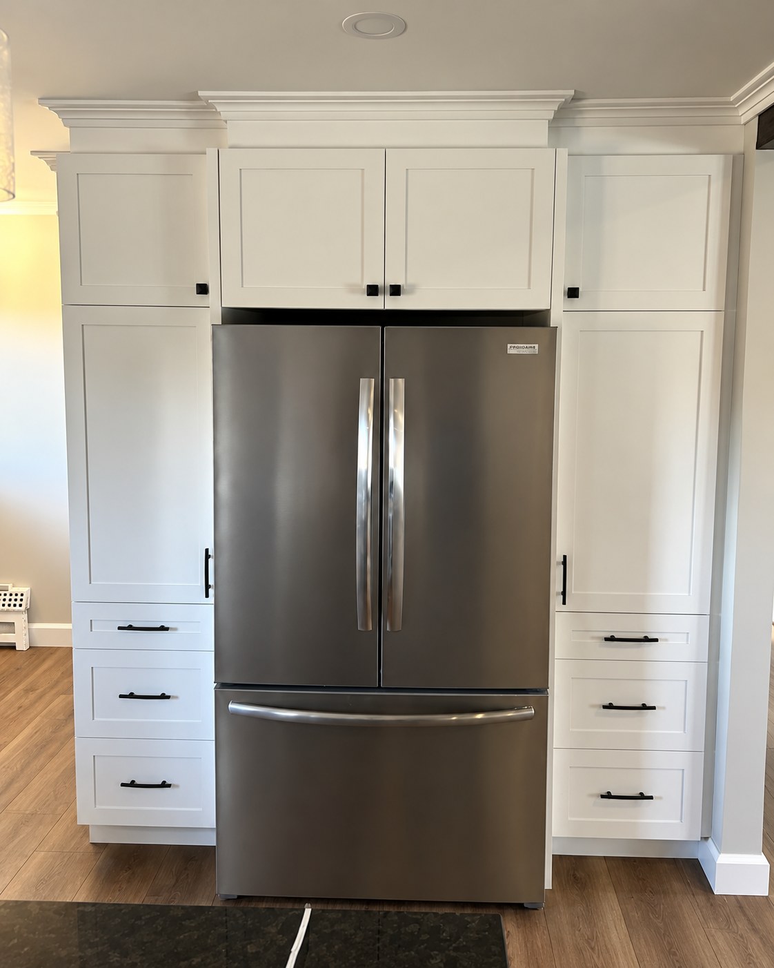 White tall cabinets and drawers around a refrigerator.