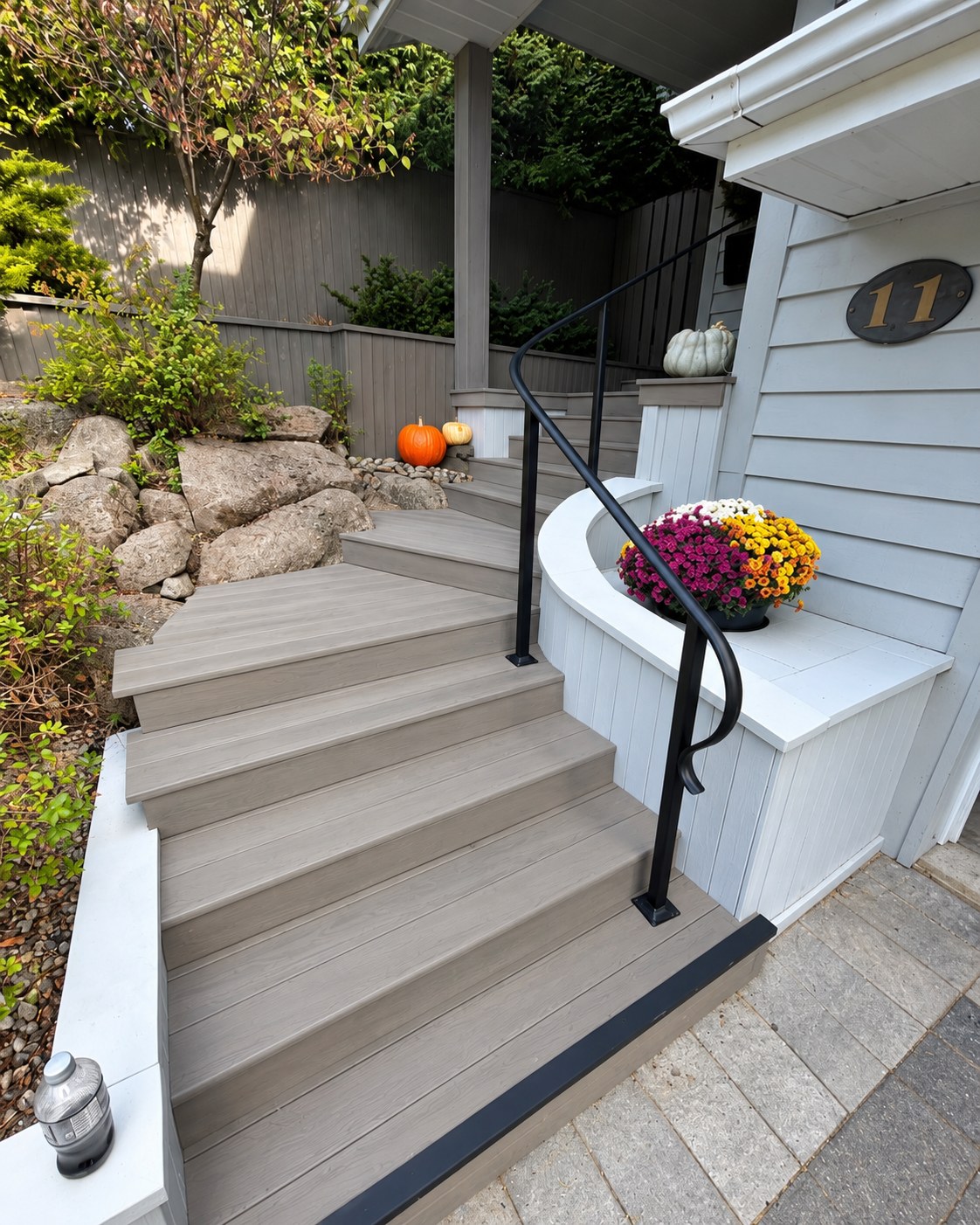 Composite front steps and a curved metal handrail.