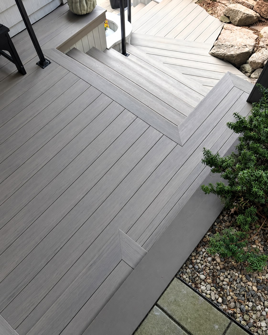 Composite landing and steps beside a stone garden border.